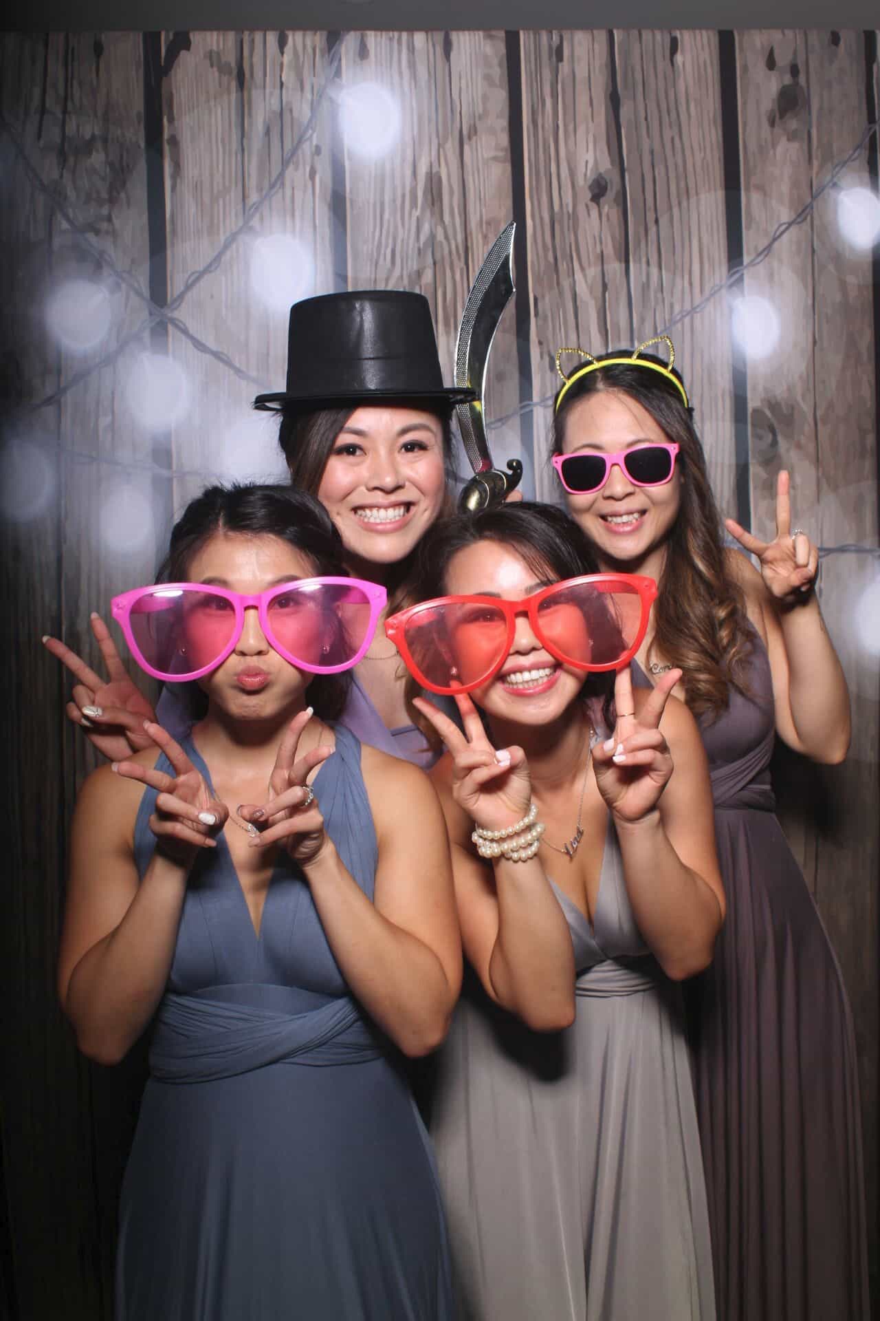 Wedding photo booth New Orleans guests posing with fun props and oversized glasses